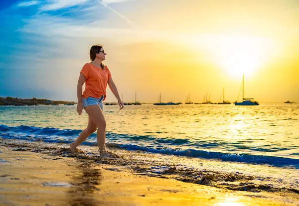 日当たりの良いビーチを歩く美しい中年の女性 ストック画像