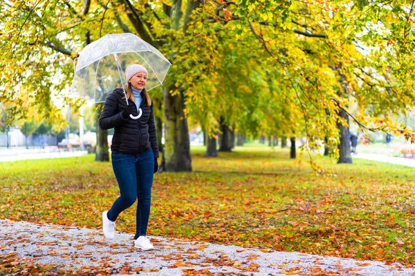 健康的なライフスタイル 傘を持っている市立公園を歩く中年女性 ストックフォト