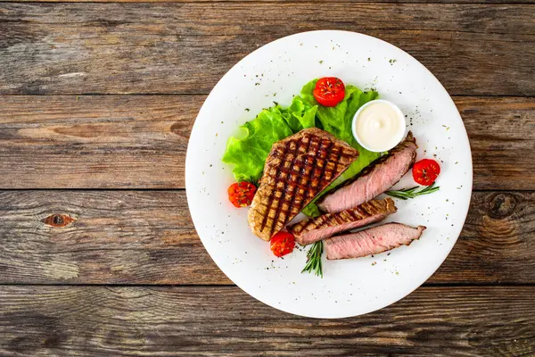 木のテーブルに新鮮な野菜とグリルビーフサーロインステーキ — ストック写真