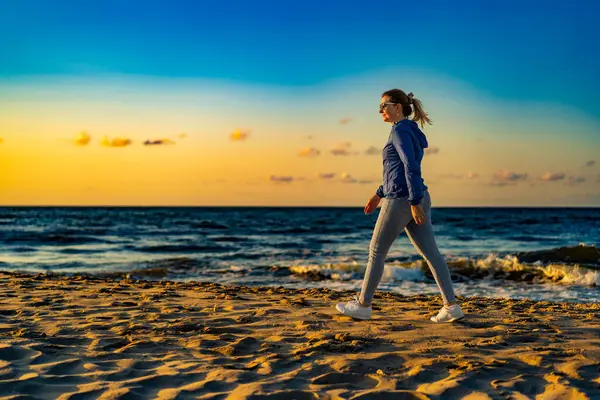 美しい中間の大人の女性は日没でビーチを歩く — ストック写真