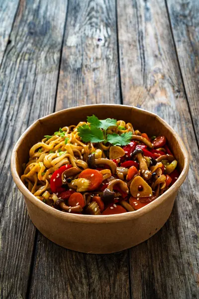 Takeaway food - Asian style stir fried vegetables and noodles on wooden table