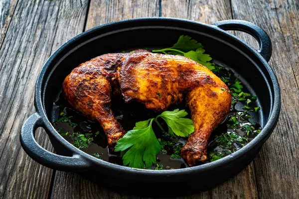 木のテーブルの調理鍋で焼いた鶏の太ももも ロイヤリティフリーのストック画像