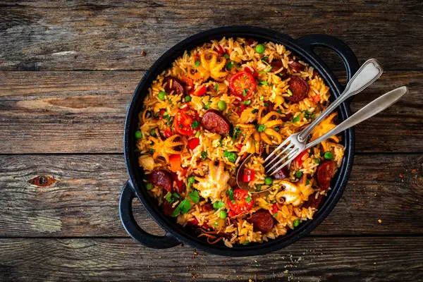 Paella Mit Meeresfrüchten Und Chorizo Der Pfanne Auf Holztisch lizenzfreie Stockfotos