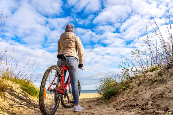 海辺で自転車に乗る中年女性 ストック写真
