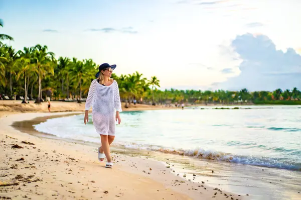 美丽的女人在阳光灿烂的海滩上散步 图库照片