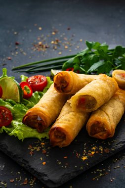 Spring rolls filled with cooked vegetables served with sauces on wooden table  clipart