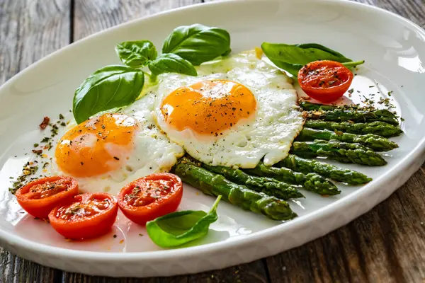 Sabroso Desayuno Huevos Soleados Con Espárragos Verdes Cocidos Tomates Fritos Fotos de stock