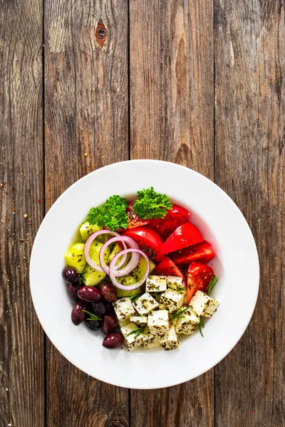 希腊风格的沙拉 新鲜蔬菜 配上意大利芝士和番石榴 放在木制桌子上的白碗里 图库图片