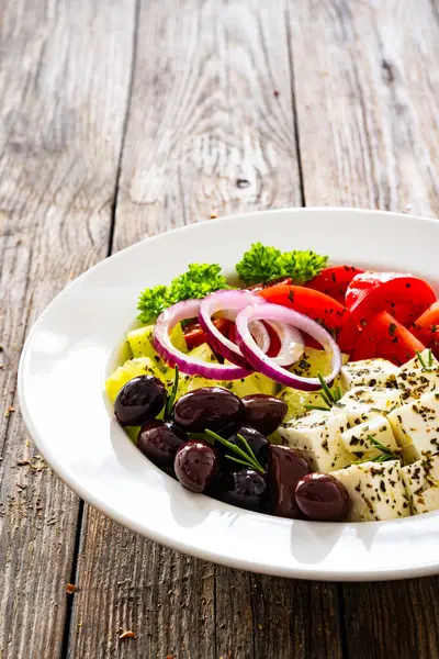 希腊风格的沙拉 新鲜蔬菜 配上意大利芝士和番石榴 放在木制桌子上的白碗里 免版税图库图片