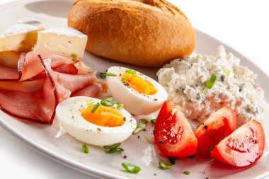  Continental breakfast - boiled eggs, white cheese, ham, tomatoes and bread roll on white background clipart