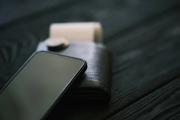 Κινητό Τηλέφωνο Δερμάτινη Τσάντα Και Στοίβα Νομισμάτων Μαύρο Ξύλινο Τραπέζι — Φωτογραφία Αρχείου
