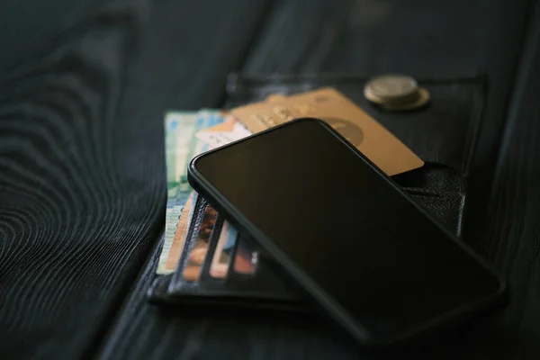 手机放在皮包上 小堆硬币放在黑色木制桌子上 金融概念 — 图库照片
