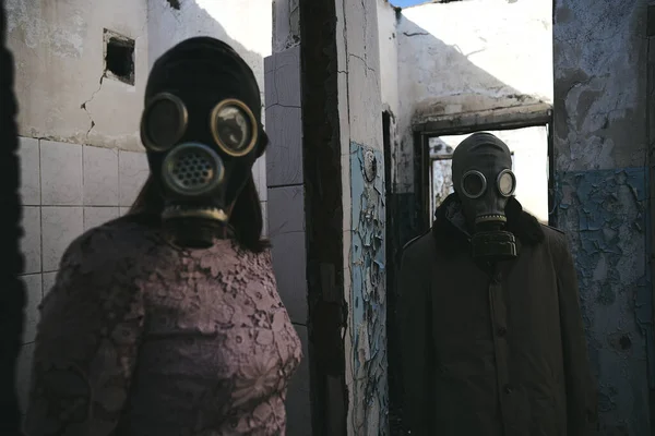 一个戴着防毒面具的女人站在被毁建筑里的一个男人面前 很适合看书 — 图库照片