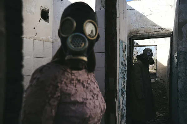 一个戴着防毒面具的女人站在被毁建筑里的一个男人面前 很适合看书 — 图库照片