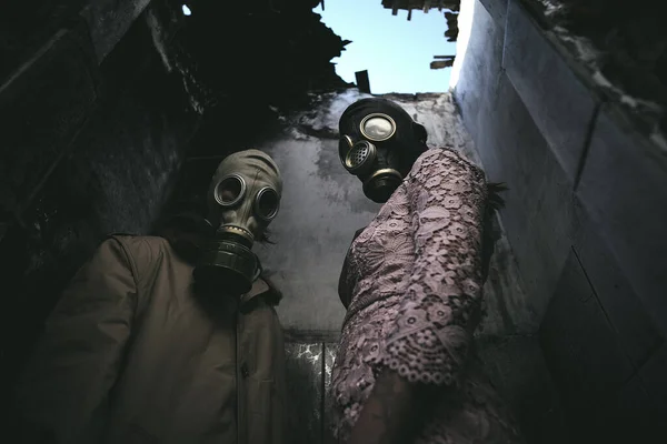 一个戴着防毒面具的男人和女人在一幢破烂不堪的大楼里 黑暗中屋顶漏水 世界末日 适合看书 角度低 — 图库照片