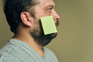 Profilde sakallı ve boş kağıt yapıştırmalarıyla kaplı bir adamın yüz resmi.