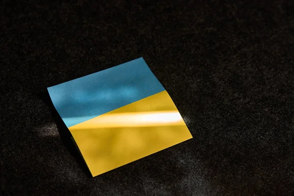 Leży Naklejka Postaci Ukraińskiej Flagi Ciemnej Powierzchni Pada Nią Promień — Zdjęcie stockowe
