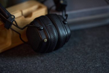 Bu parlak siyah kulaklıklar yumuşak, karanlık bir yüzeye oturmuş, evdeki büyük bir dinleme deneyimi için hazırlar..