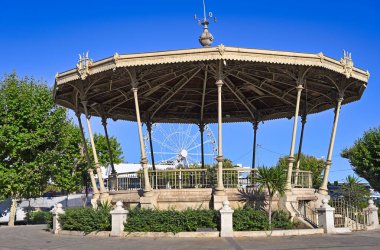 A bandstand and ferris wheel in Cannes city France summer season clipart
