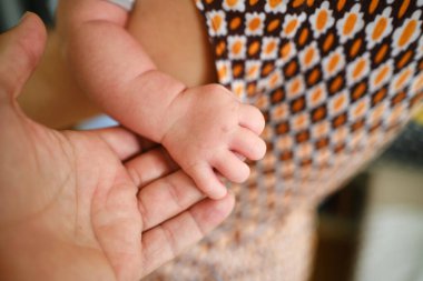 Yeni doğmuş bebek babasını tutuyor. Çocuğun küçük eli, anne ve babanın avuç içi..