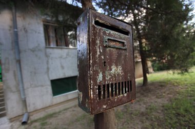 Bahçedeki eski paslı posta kutusu. Terk edilmiş bir evin kapısının yakınındaki paslı posta kutusu.. 