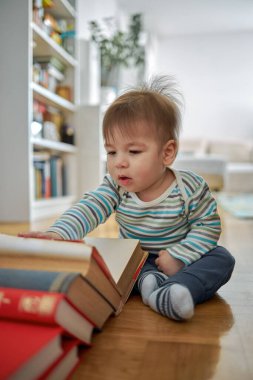 Şirin bir bebek oturuyor ve büyük bir kitaba bakıyor.. 