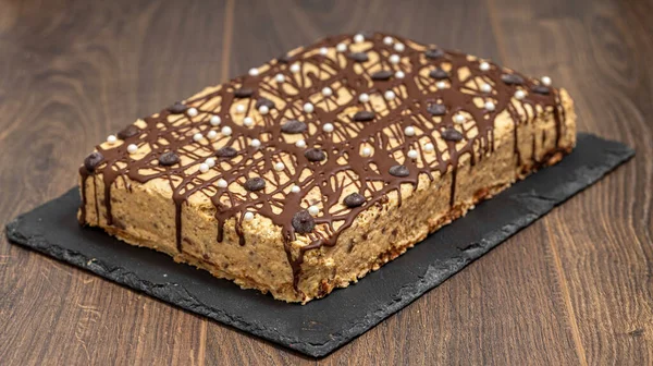 有坚果奶油的巧克力蛋糕放在木制桌子上 盘子里的一块蛋糕 — 图库照片
