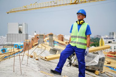 İnşaat alanında duran gülümseyen inşaat işçisi.