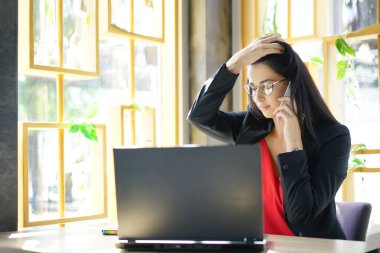 Kameraya gülümseyen dizüstü bilgisayarlı, modern ofiste çalışan gözlüklü mutlu esmer iş kadını. Başarılı Girişimcilik ve Kariyer Konsepti.                            