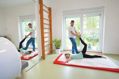 Genç bir kadın terapist tarafından Tayland masajı görüyor. Geleneksel Asya esneme terapisi.