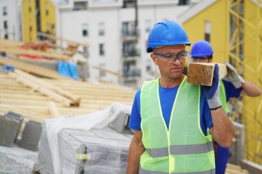 Construction workers carrying wooden plank at building site outdoors