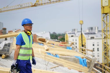 İnşaat işçisi, inşaat alanının yakınında yürüyen güvenlik donanımı giyiyor.