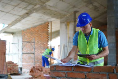 Male construction worker reviewing blueprints at building site