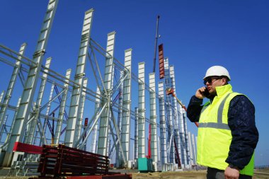 İnşaat alanında işçi kadrosu ya da beyaz koruyucu başlık takan mühendis. Açık havada.                            