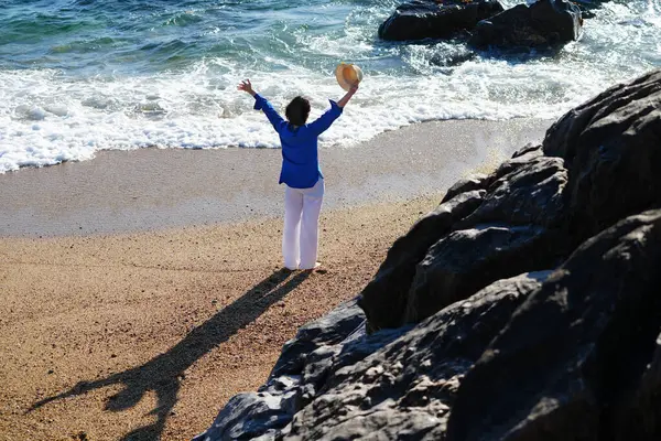 Genç bir kadın Portekiz, Porto 'da kumlu ve mavi gökyüzü olan boş bir kumsalın keyfini çıkarıyor..