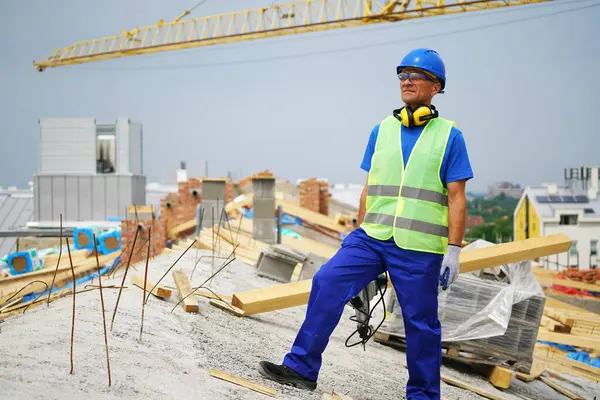 İnşaat alanında duran gülümseyen inşaat işçisi.