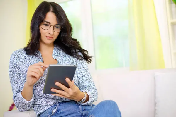 Zarif genç kadın iş kadını evde kanepede oturan bir dizüstü bilgisayar kullanarak                             