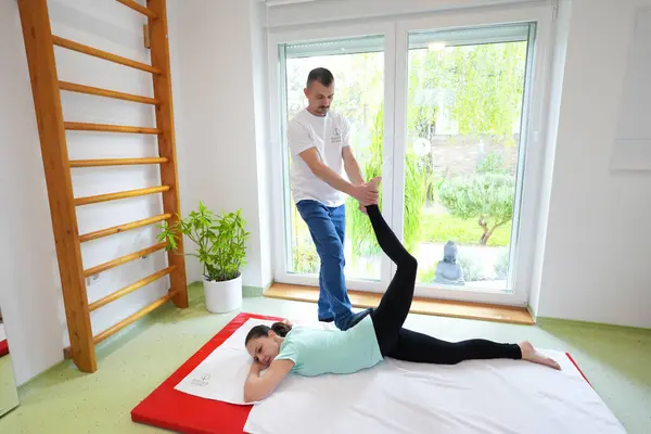 Genç bir kadın terapist tarafından Tayland masajı görüyor. Geleneksel Asya esneme terapisi.
