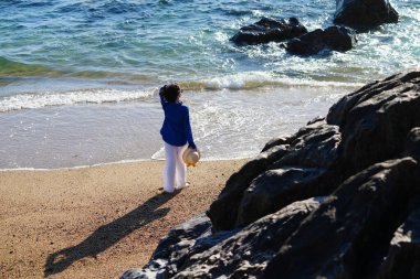 Genç bir kadın Portekiz, Porto 'da kumlu ve mavi gökyüzü olan boş bir kumsalın keyfini çıkarıyor..