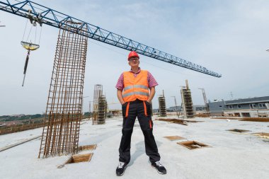 Kendine güvenen inşaat işçisi inşaat alanında gururla duruyor.