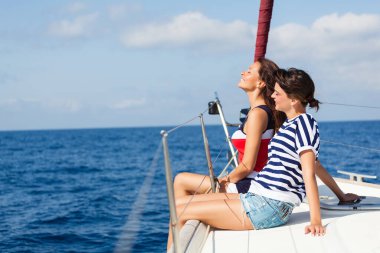 Yelkenlide dinlenen iki kadın güneşli okyanus esintisinin tadını çıkarıyor.