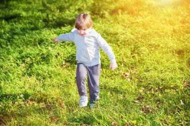 Genç bir çocuk açık yeşil çimlerde koşuyor.