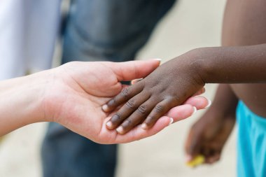 El ele tutuşmak. Afrikalı siyahi bir kızın elini tutan beyaz bir kadın.