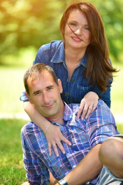 Güneşli bir öğleden sonra dışarıda dinlenen gülümseyen çift.