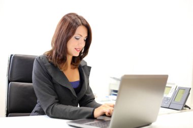 Gülümseyen iş kadını modern ofis bilgisayarında daktilo yazıyor.