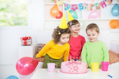 Üç küçük çocuk doğum günü partisini birlikte kutluyor.