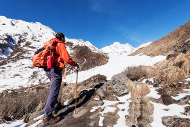 Karlı dağ manzarasında yürüyüp açık gökyüzünün altında sırt çantasıyla dolaşmak
