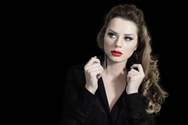 Siyah arka planda poz veren siyah elbiseli bir kadın.