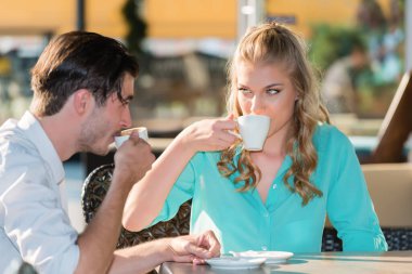Açık kafe masasında kahve içen genç çift.