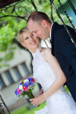 Gülümseyen gelin dışarıda damadın yanında duruyor.